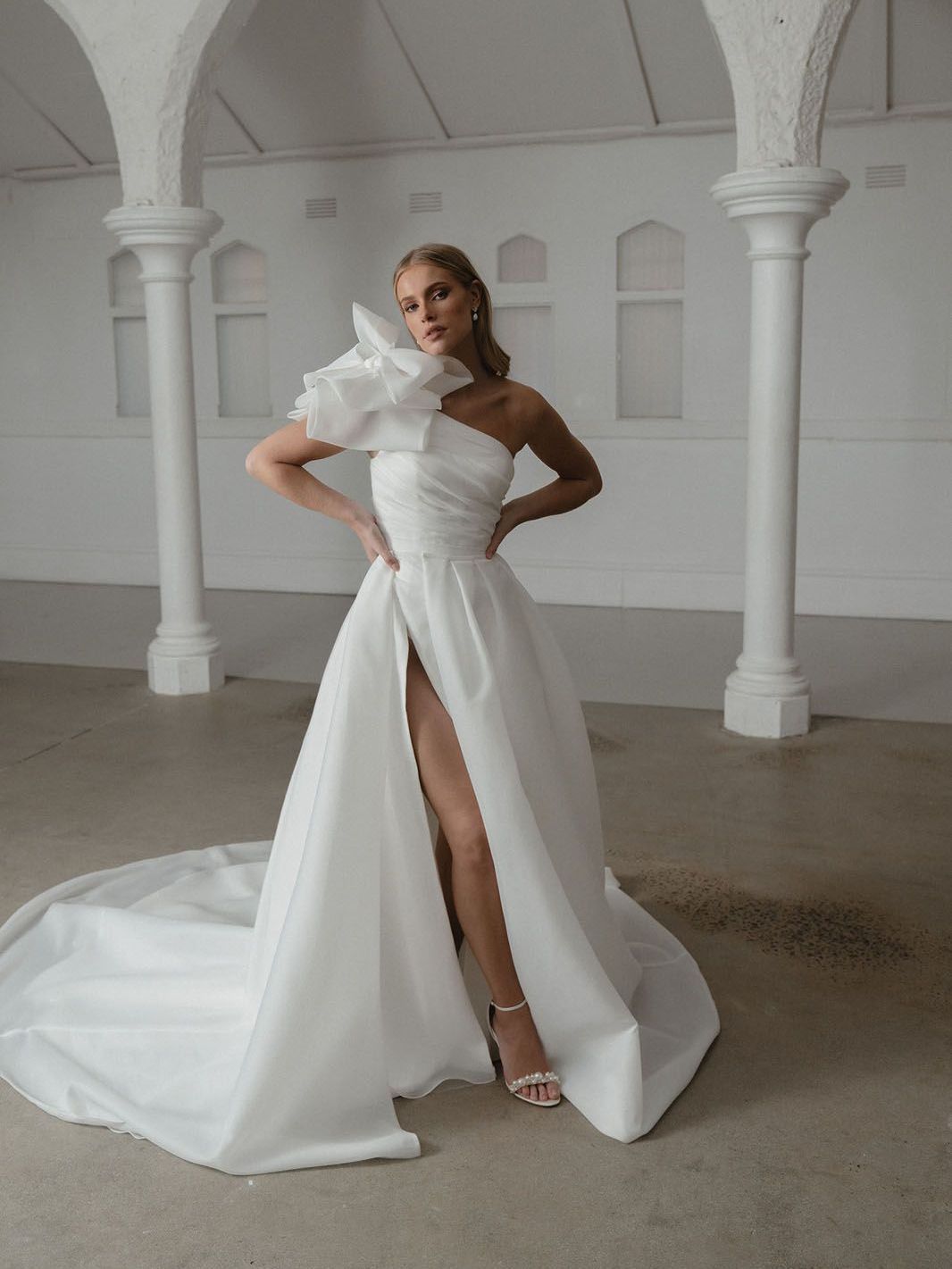 Eine Frau trägt ein weißes Brautkleid mit hohem Schlitz.