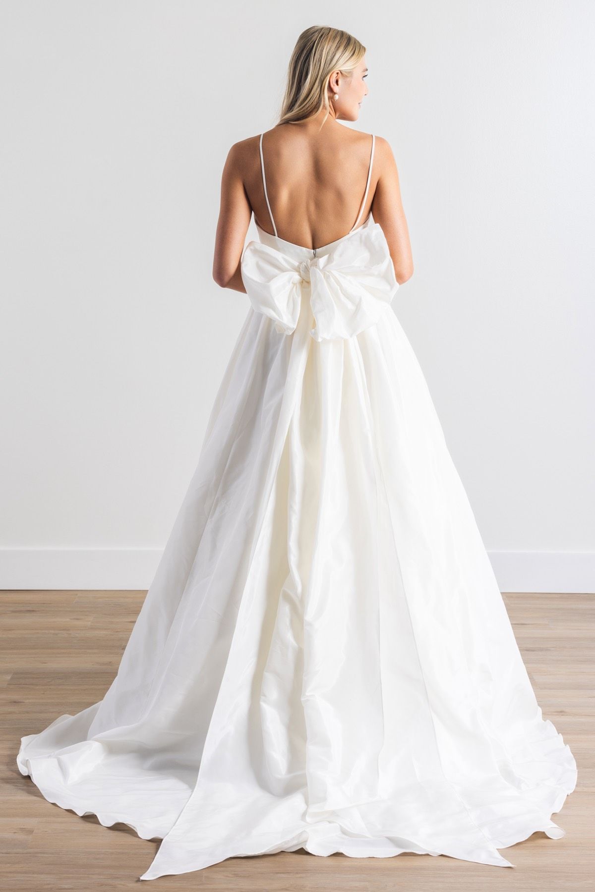 Eine Frau in einem weißen Brautkleid steht in einem Raum.