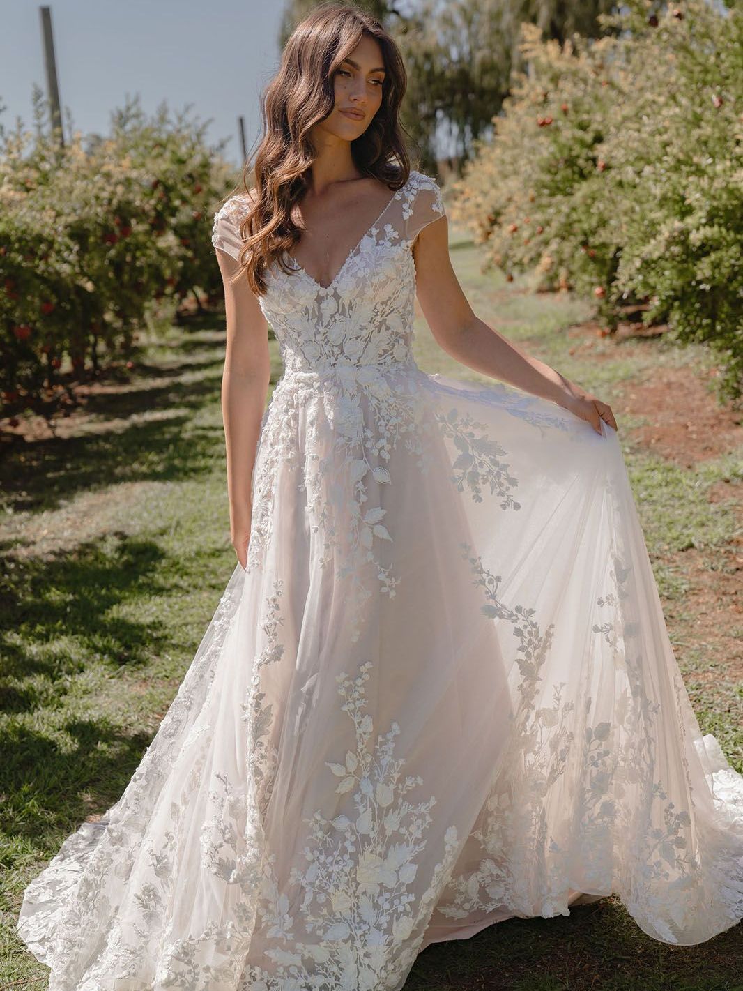 Eine Frau in einem weißen Brautkleid steht auf einem Feld.
