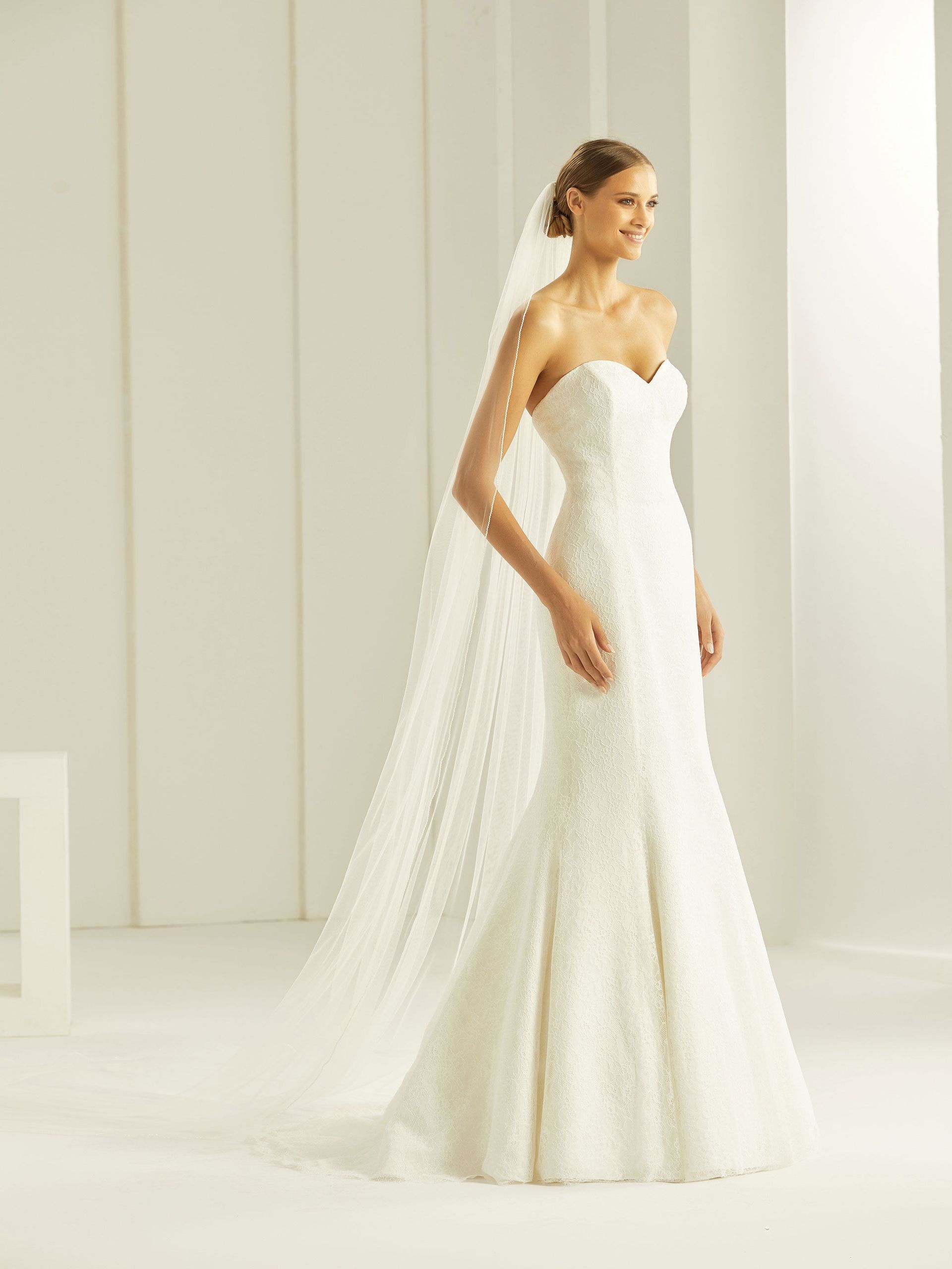 Eine Frau in einem Brautkleid und Schleier steht in einem Raum.