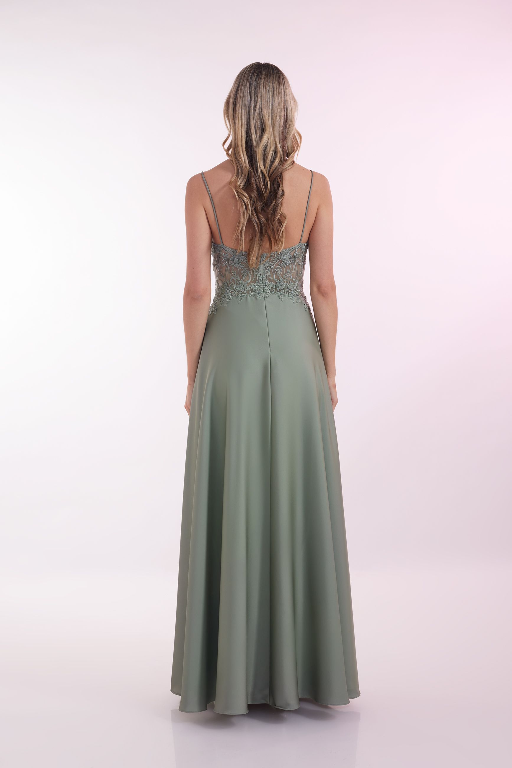 Eine Frau in einem grünen Kleid steht vor einer Holztür.