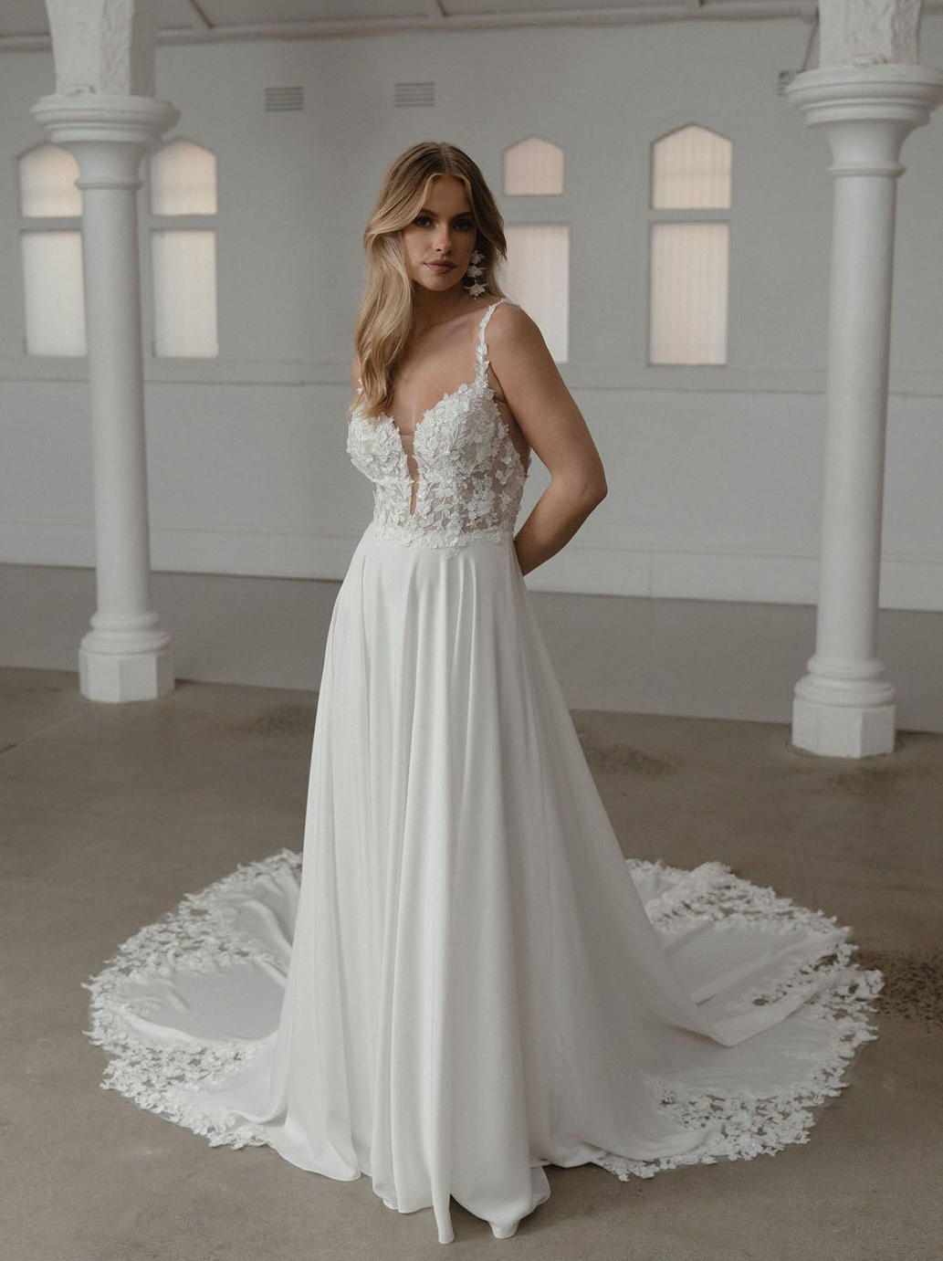 Eine Frau in einem weißen Brautkleid steht in einem Raum mit Säulen.