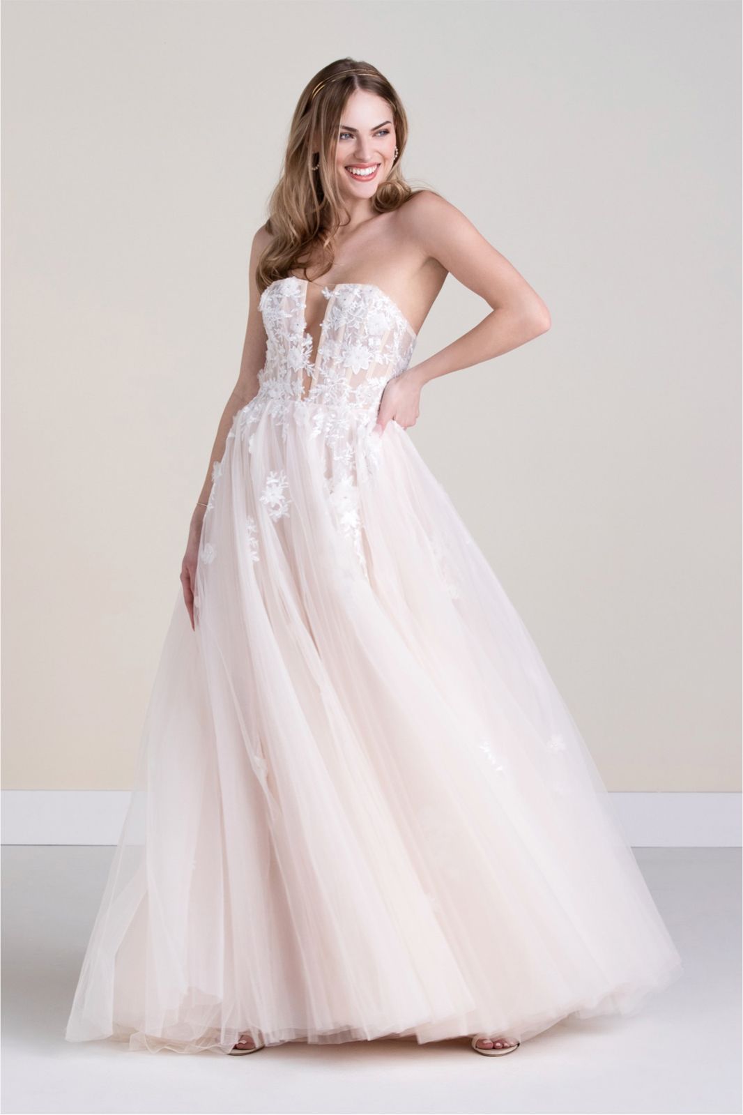 Eine Frau in einem weißen Kleid steht vor Blumen.