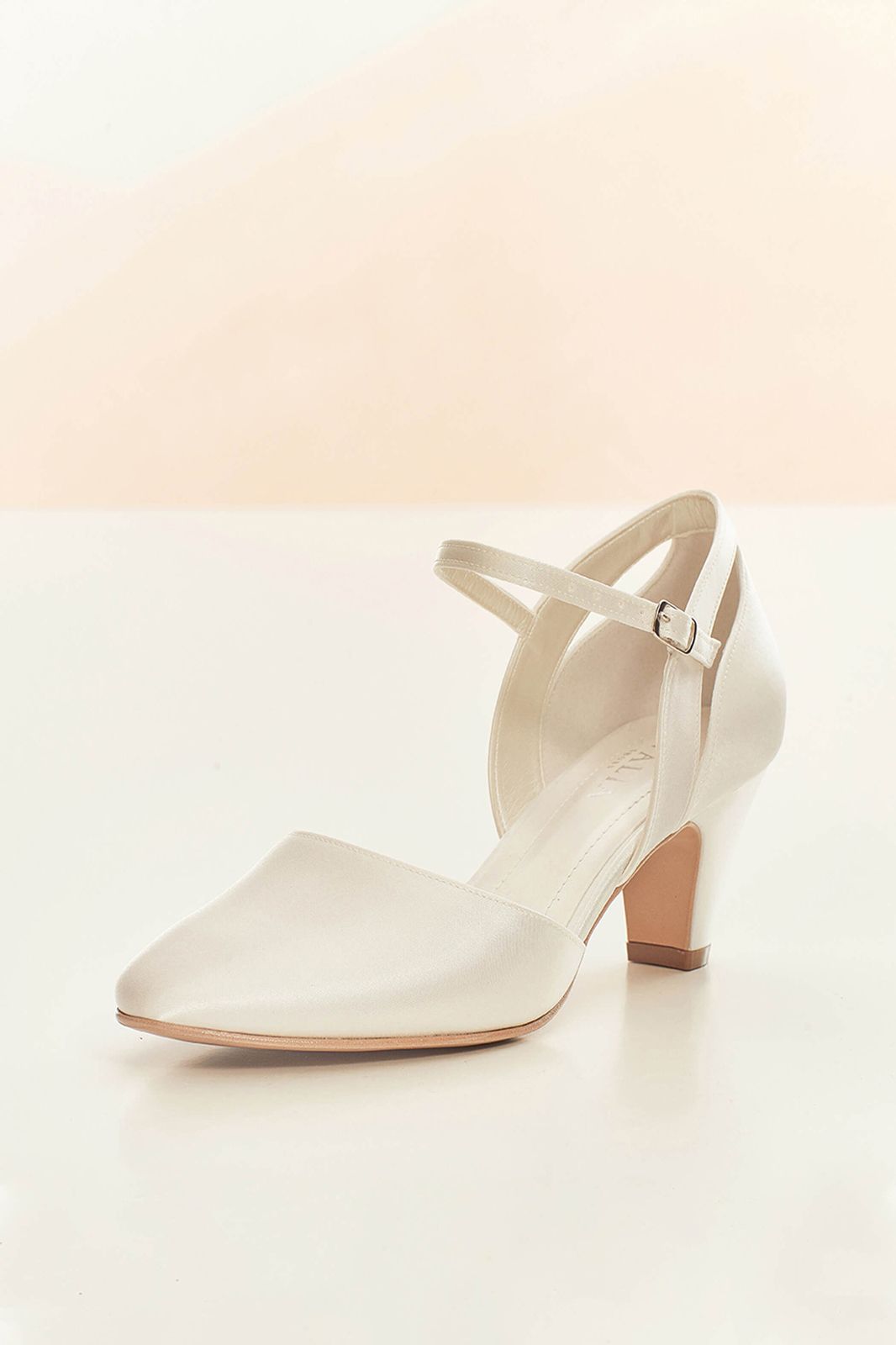 Ein Paar weiße Brautschuhe mit einer Schnalle um den Knöchel auf einer weißen Fläche.