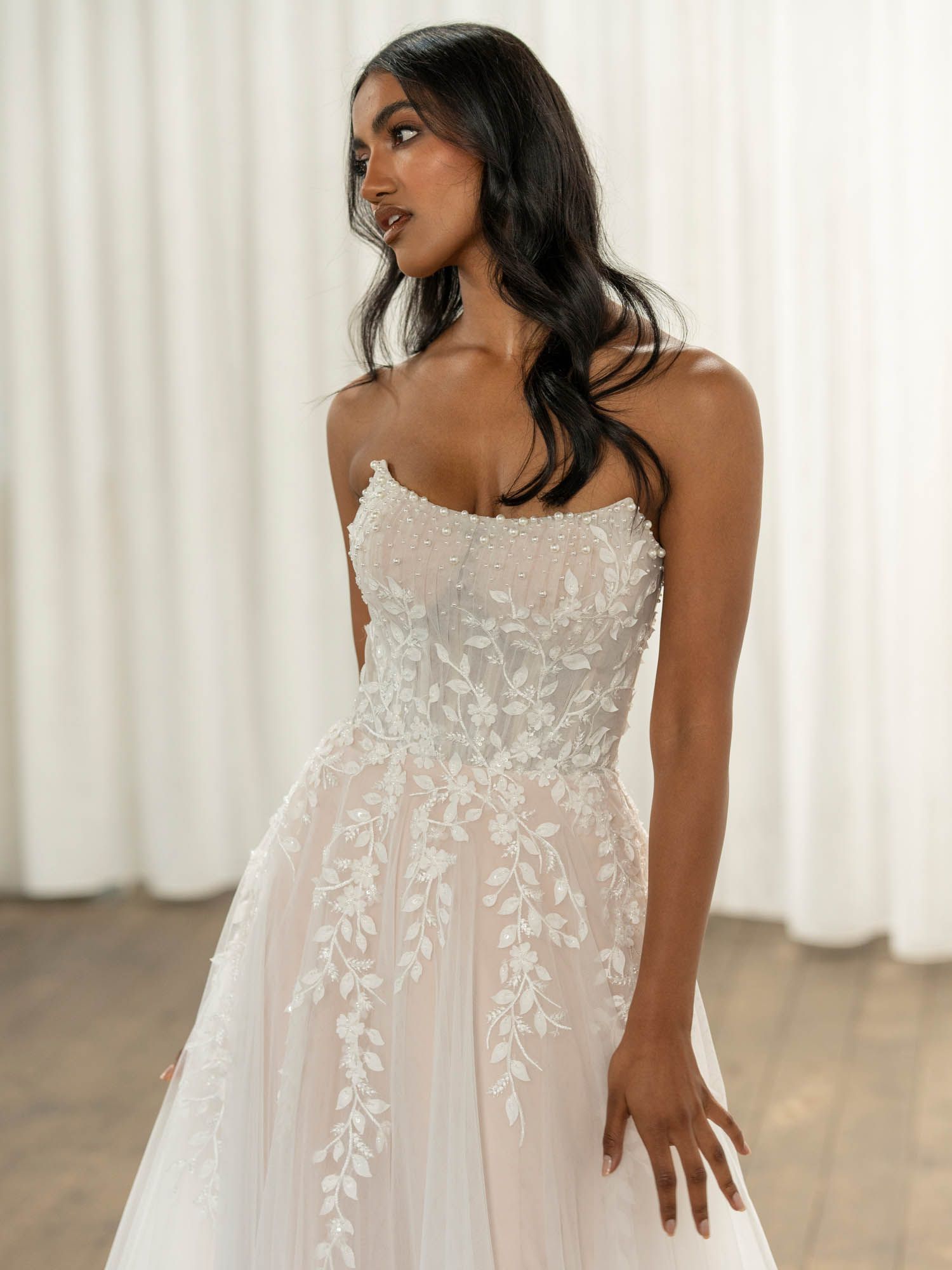 Eine Frau in einem Brautkleid steht an einem steinigen Strand.