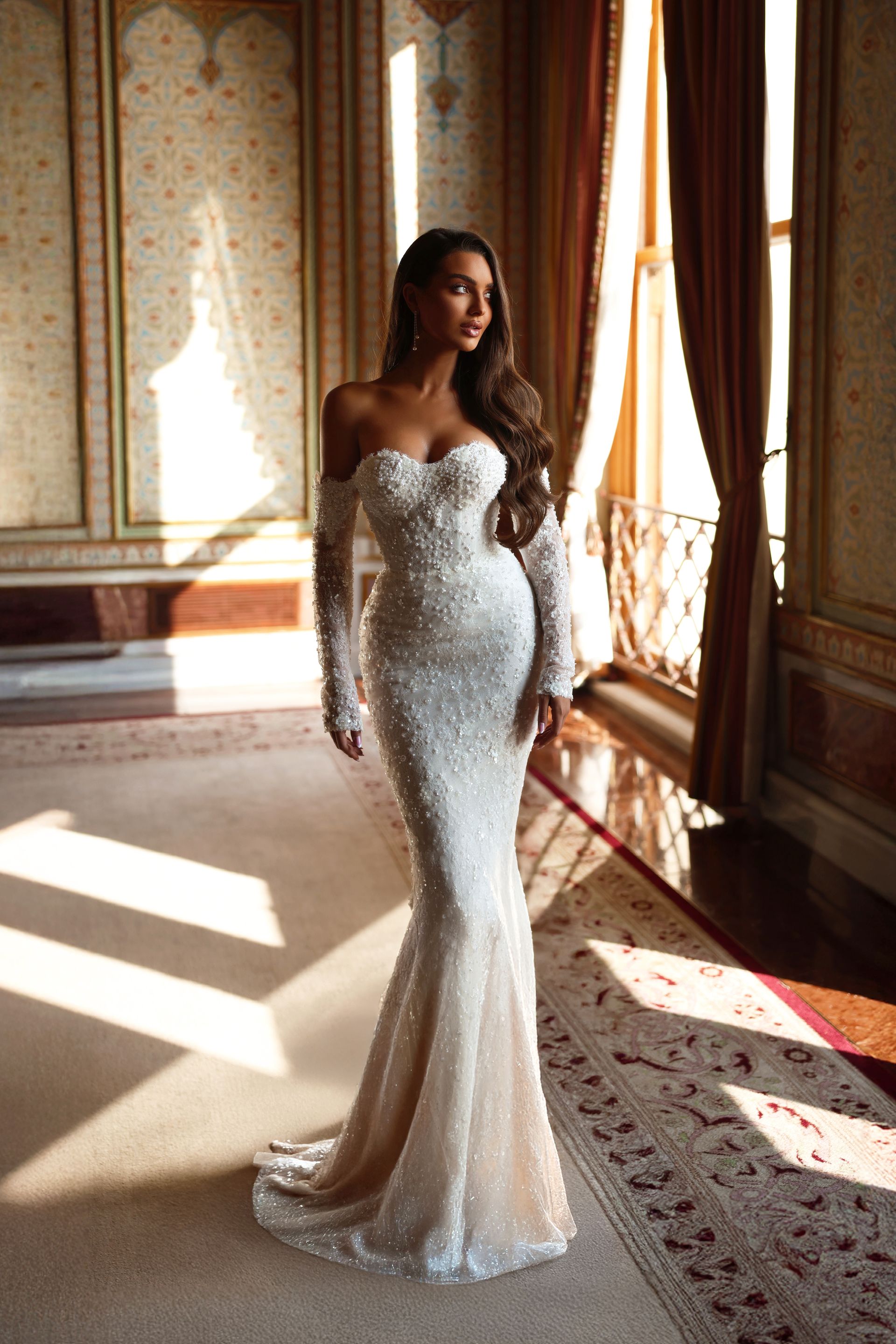 Eine Frau trägt ein weißes Brautkleid mit langen Ärmeln.