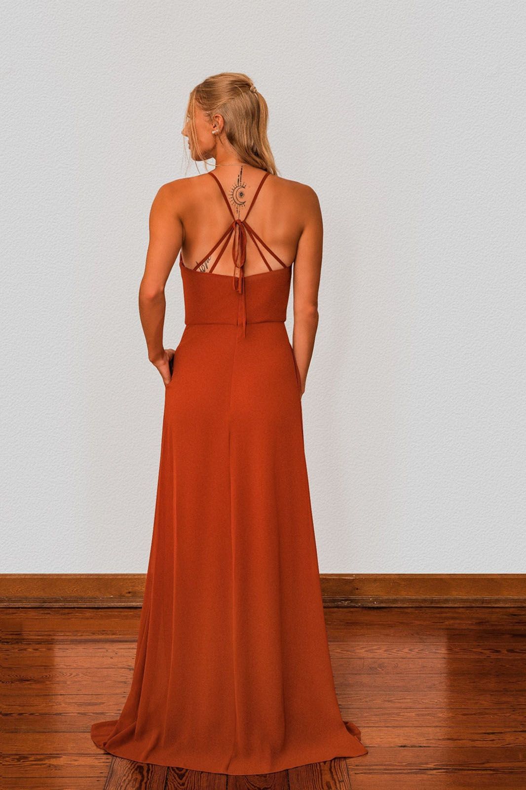 Zu sehen ist der Rücken einer Frau in einem orangefarbenen Kleid.