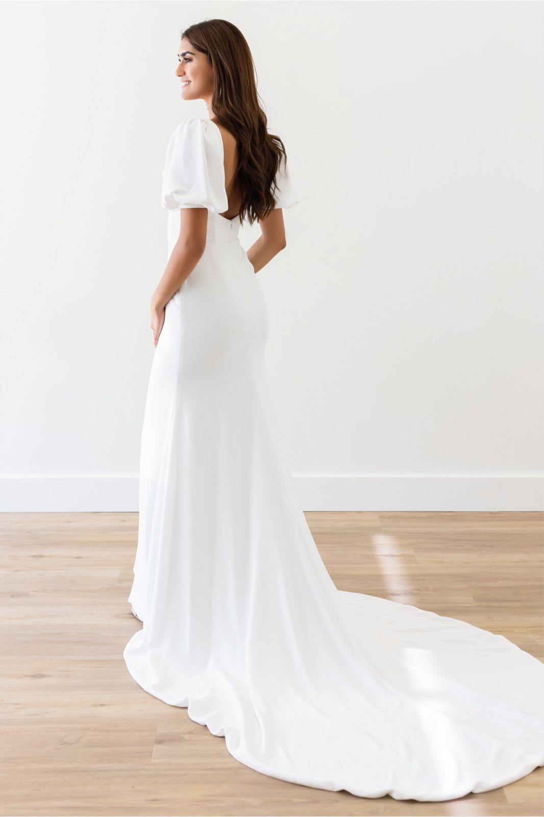 Eine Frau in einem Brautkleid steht auf einer Treppe vor einem Gebäude.