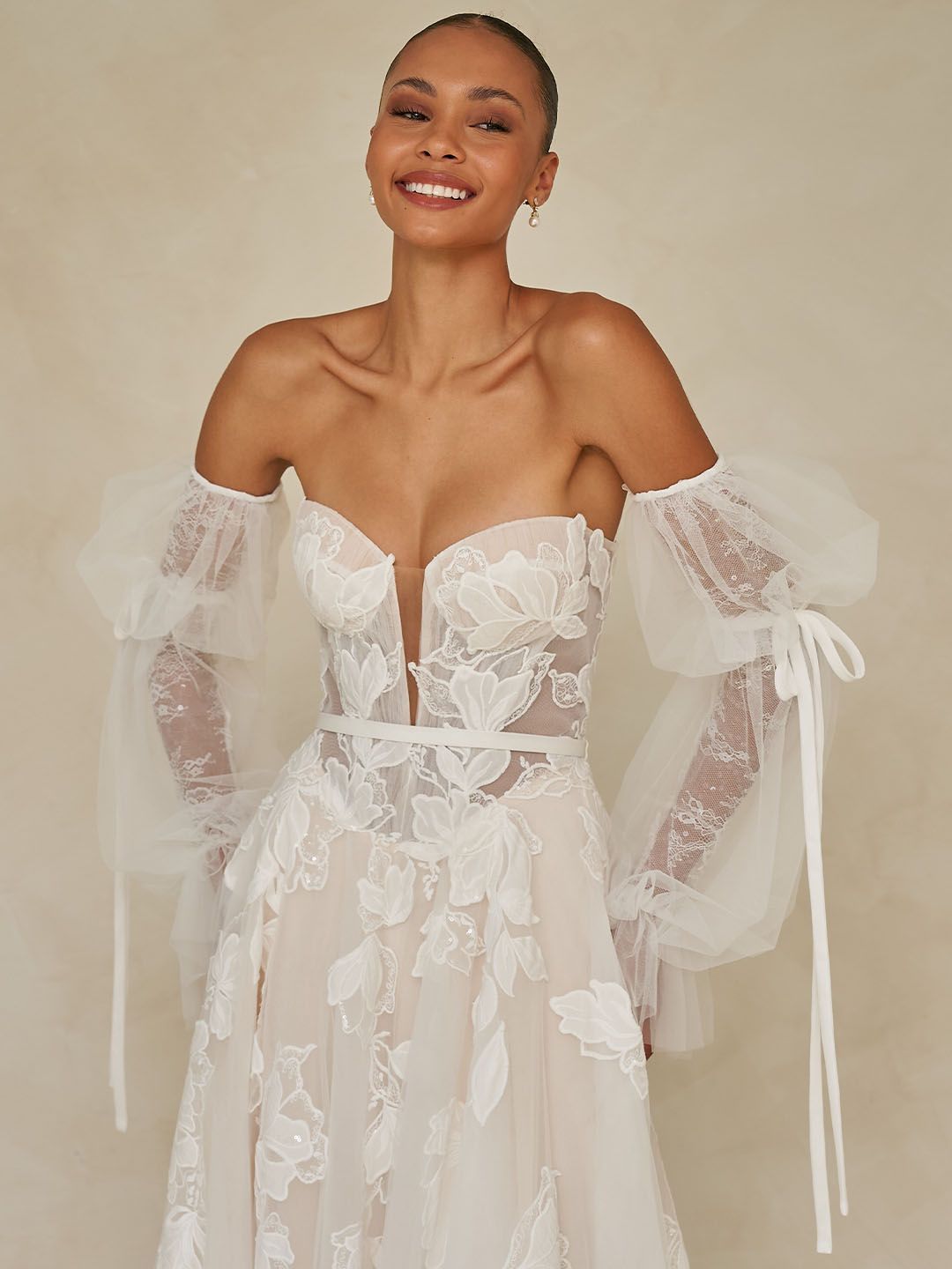 Eine Frau in einem Brautkleid steht vor Blumen.