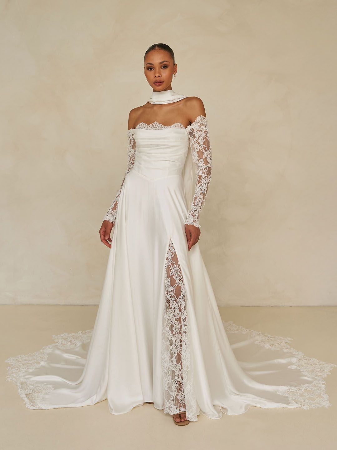 Eine Frau in einem Brautkleid steht vor einer Wand aus rosa Blumen.