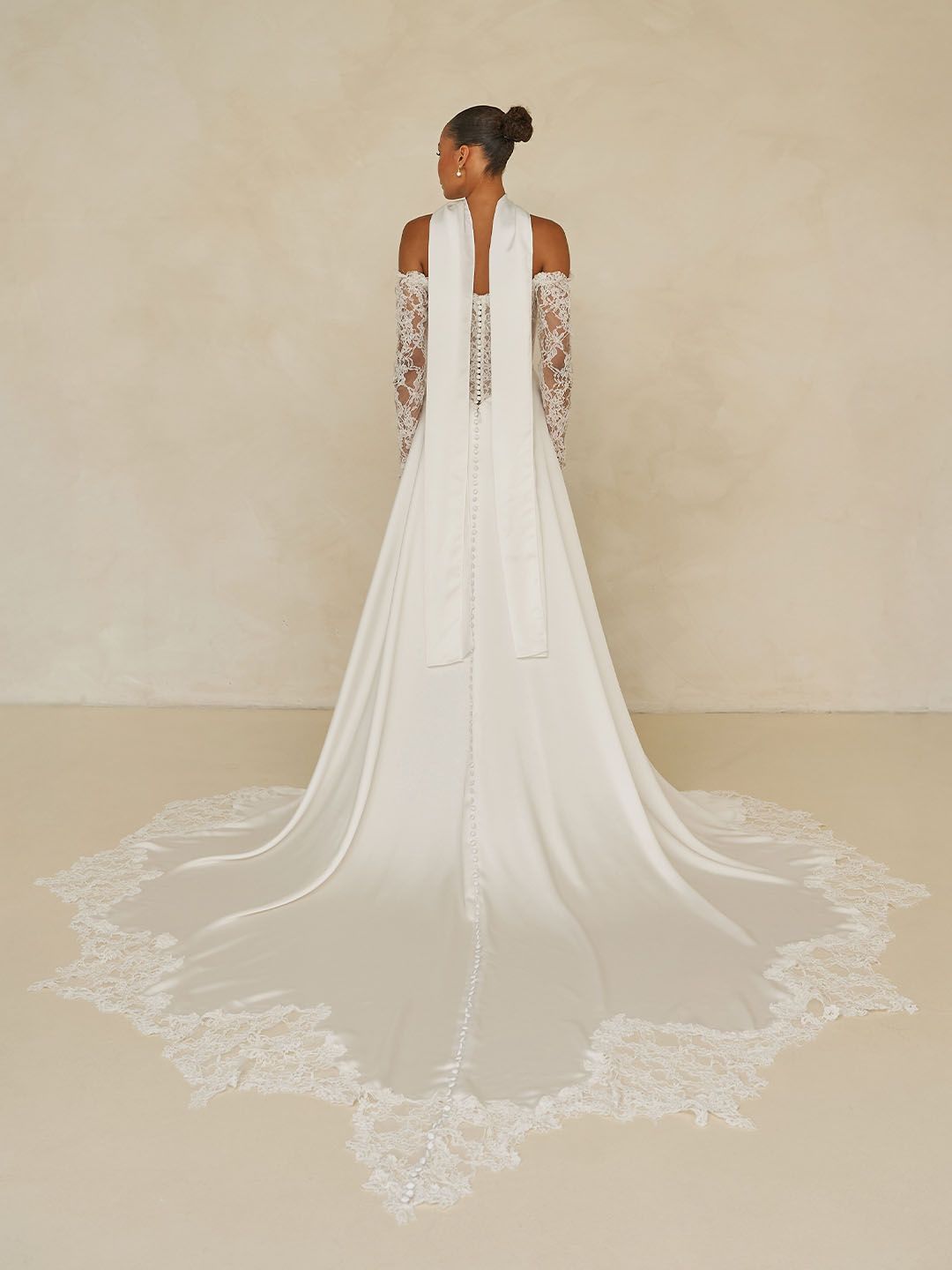 Eine Frau in einem Brautkleid steht vor einer Blumenwand.