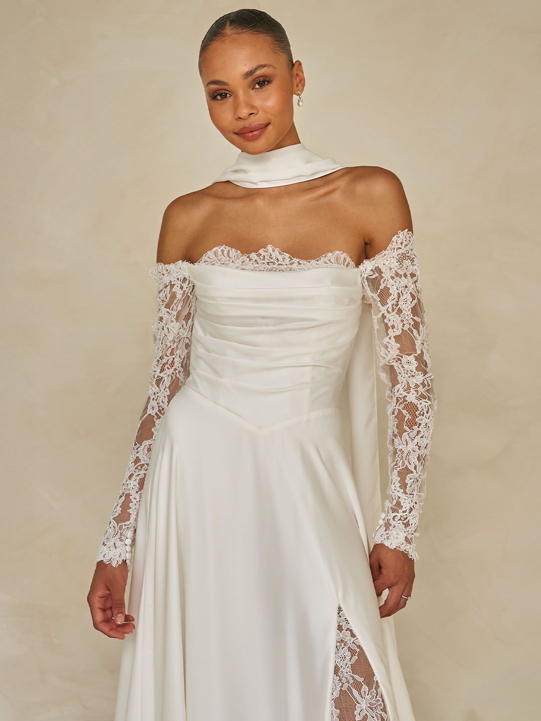 Eine Frau in einem weißen Brautkleid steht vor Blumen.