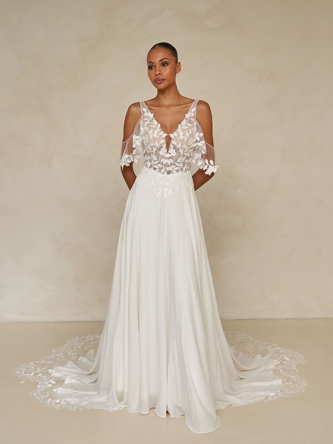 Eine Frau in einem Brautkleid steht vor einer Blumenwand.