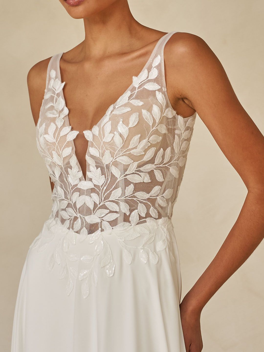 Eine Frau in einem weißen Brautkleid steht vor Blumen.