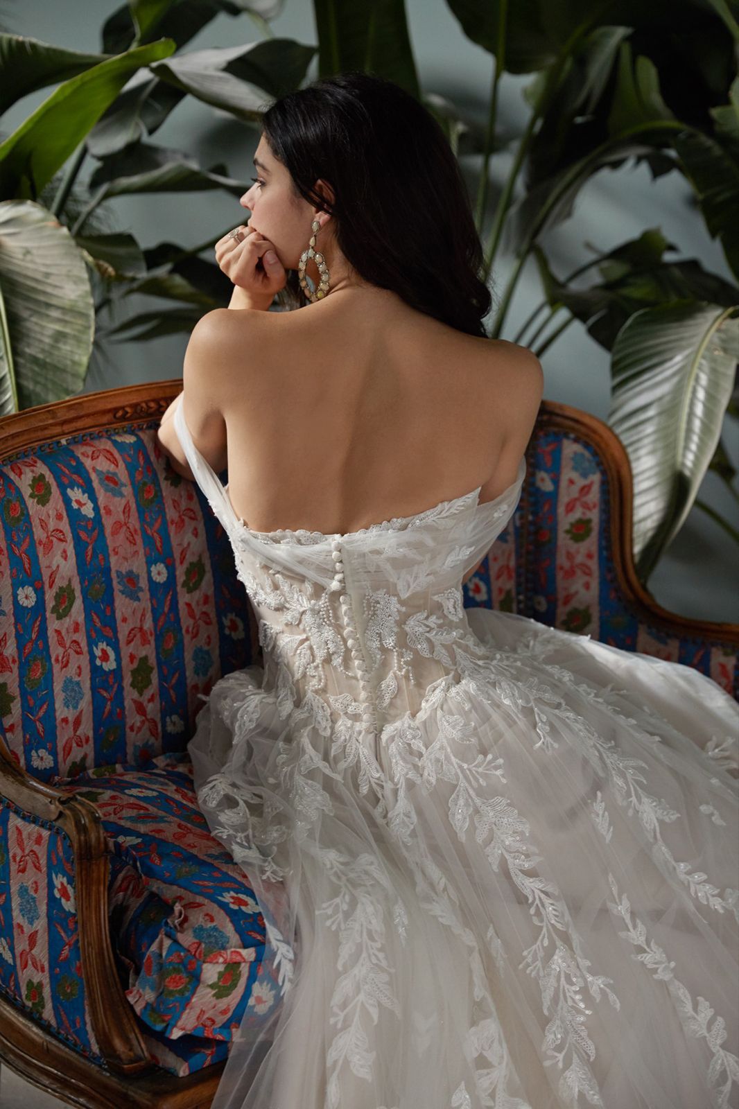 Eine Frau in einem weißen Kleid steht vor Blumen.