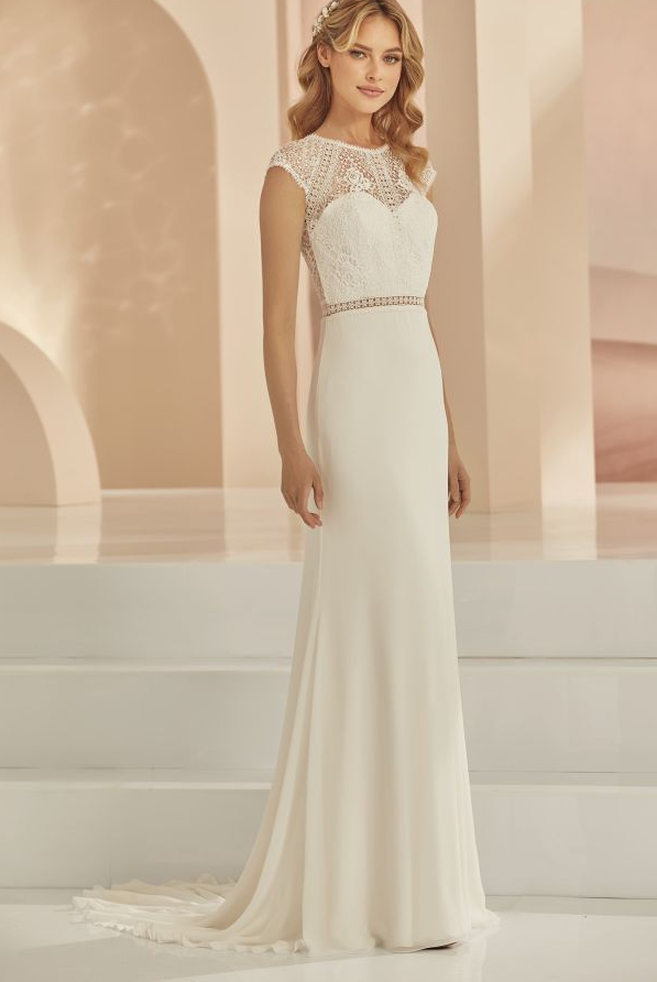 Eine Frau in einem Brautkleid steht vor einem Gebäude.