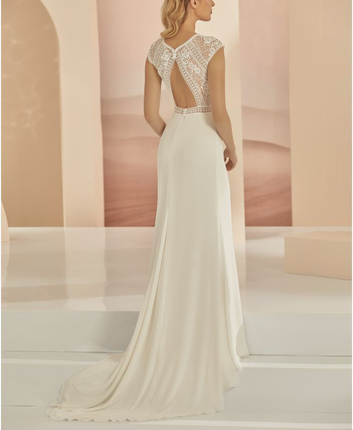 Eine Frau in einem Brautkleid steht auf einer Treppe vor einem Gebäude.