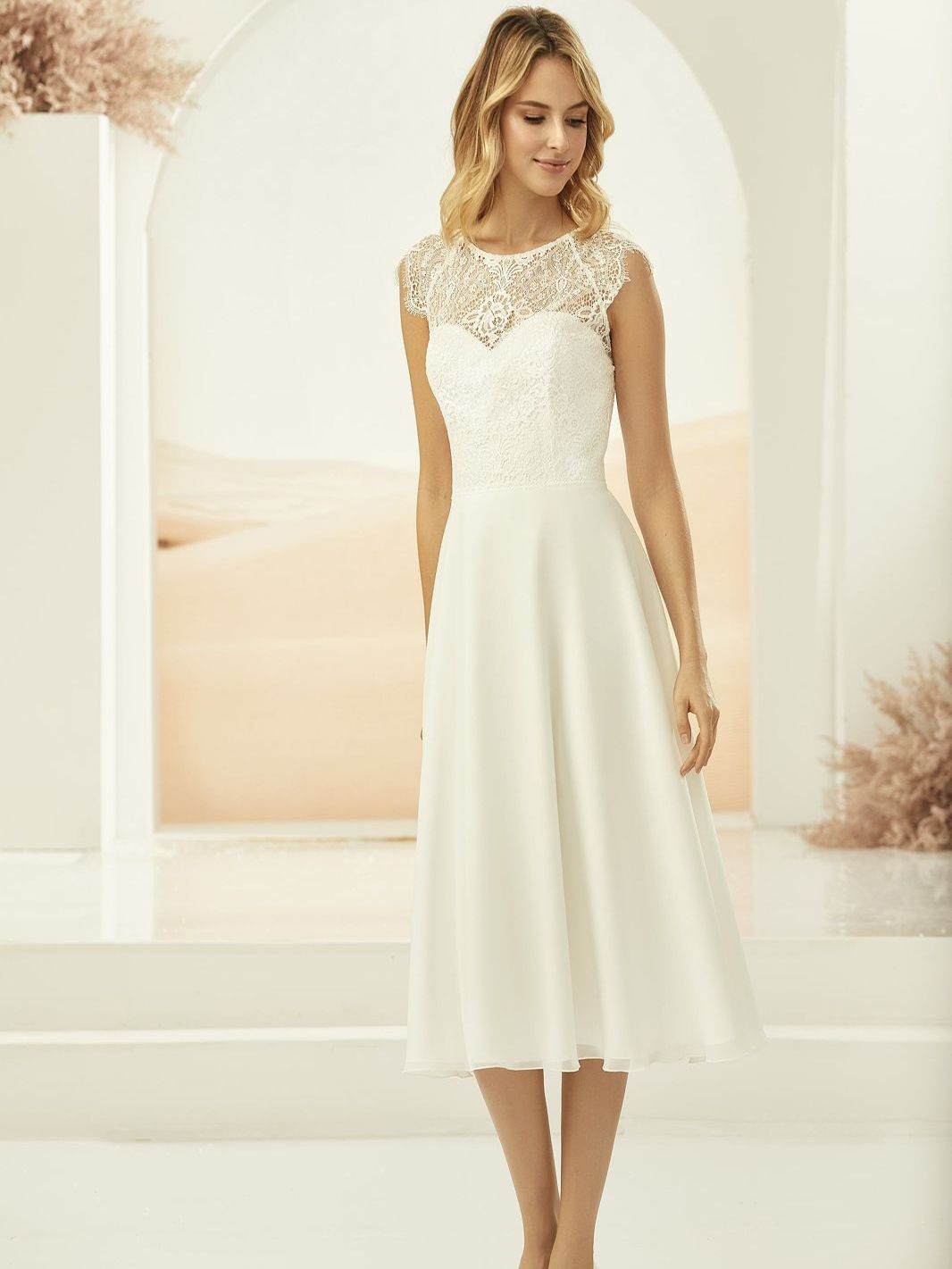 Eine Frau trägt ein weißes Hochzeitskleid und weiße Schuhe.