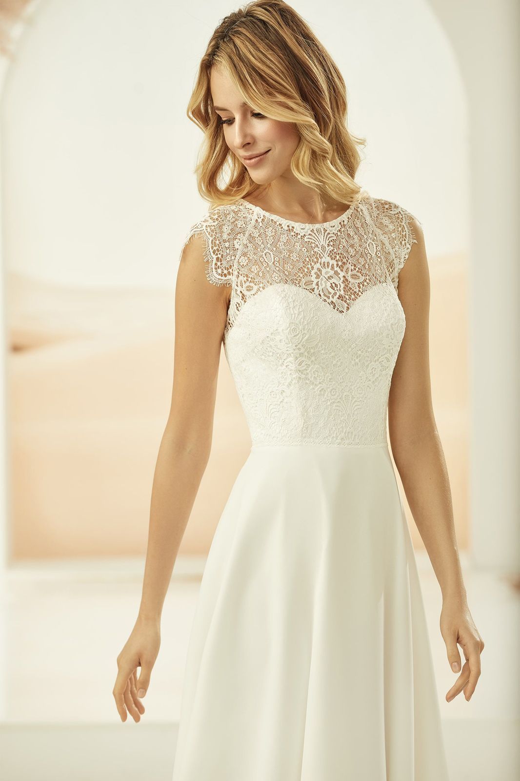 Eine Frau trägt ein weißes Brautkleid mit Spitzenoberteil.