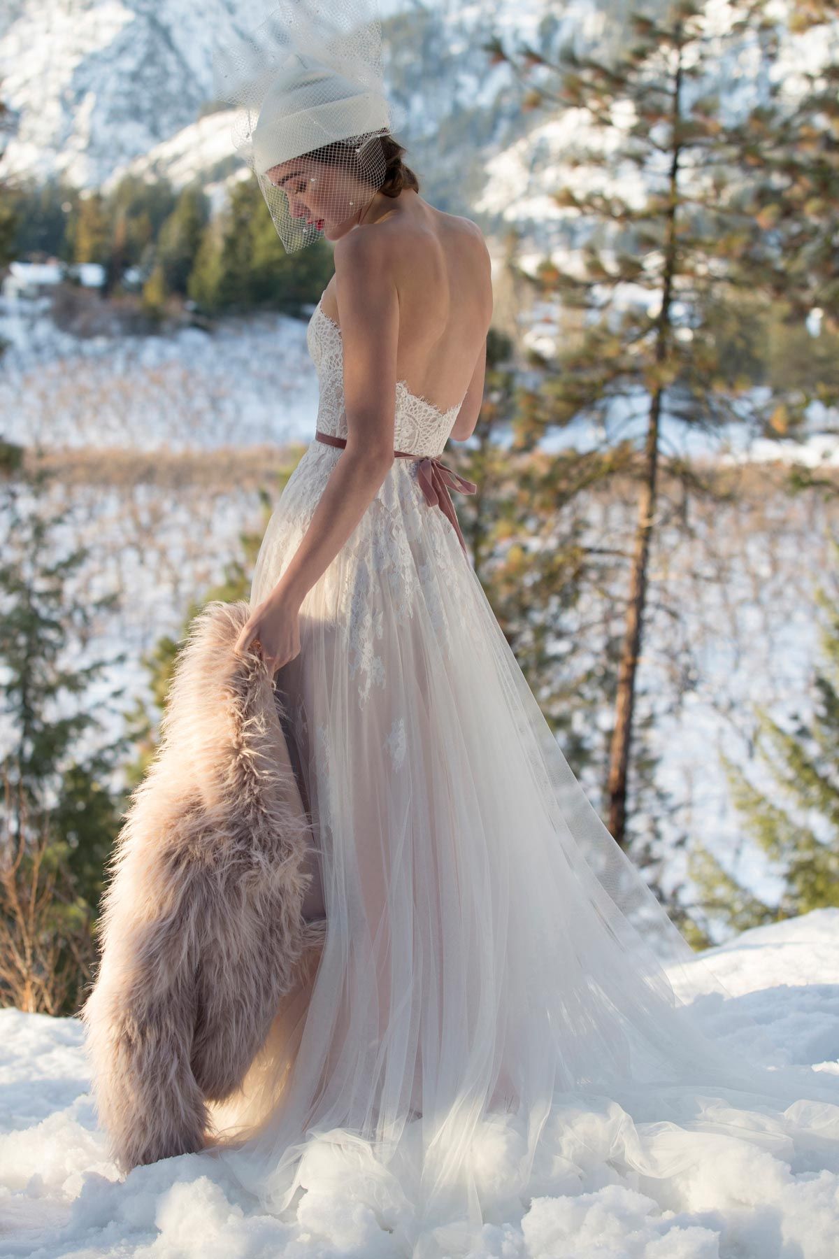 Der Rücken einer Frau in einem Brautkleid mit langer Schleppe.