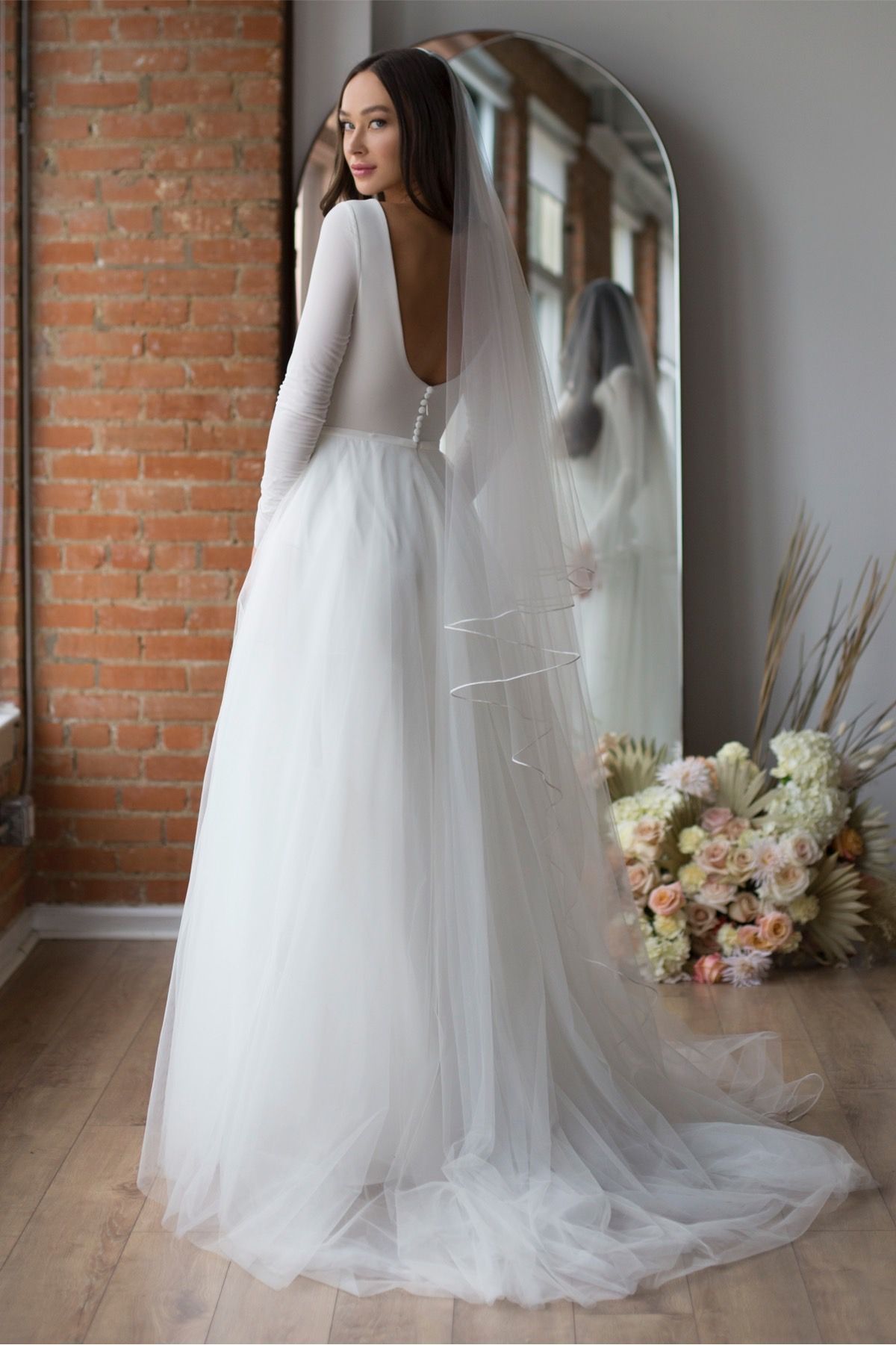 Eine Frau in einem Brautkleid steht auf einer Treppe vor einem Gebäude.