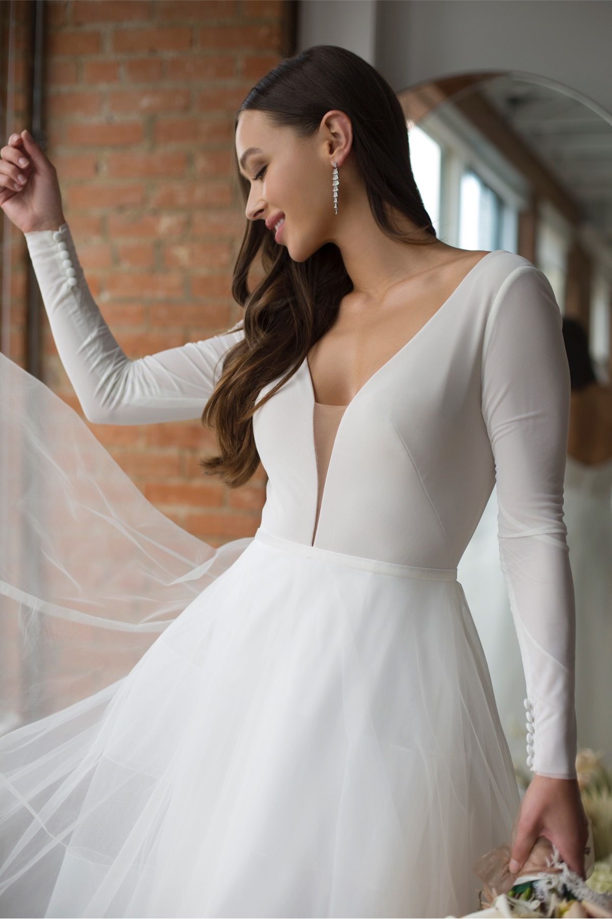 Eine Frau in einem weißen Kleid steht vor Blumen.