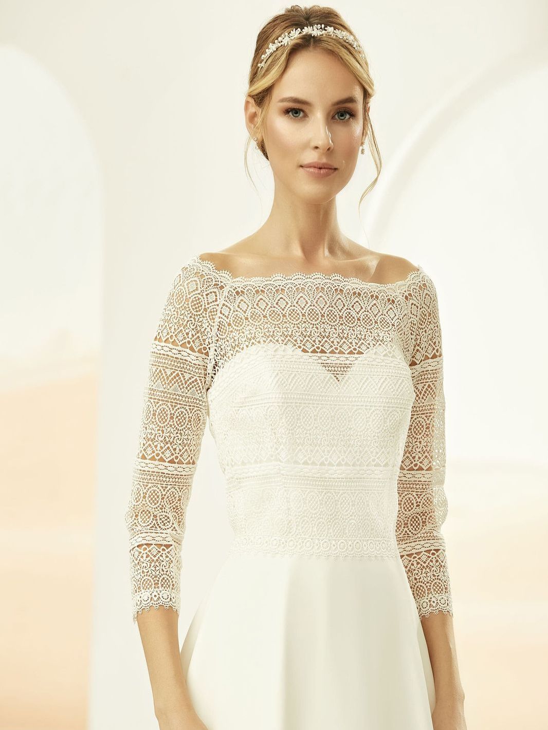 Eine Frau in einem Brautkleid trägt ein Spitzentop mit langen Ärmeln.