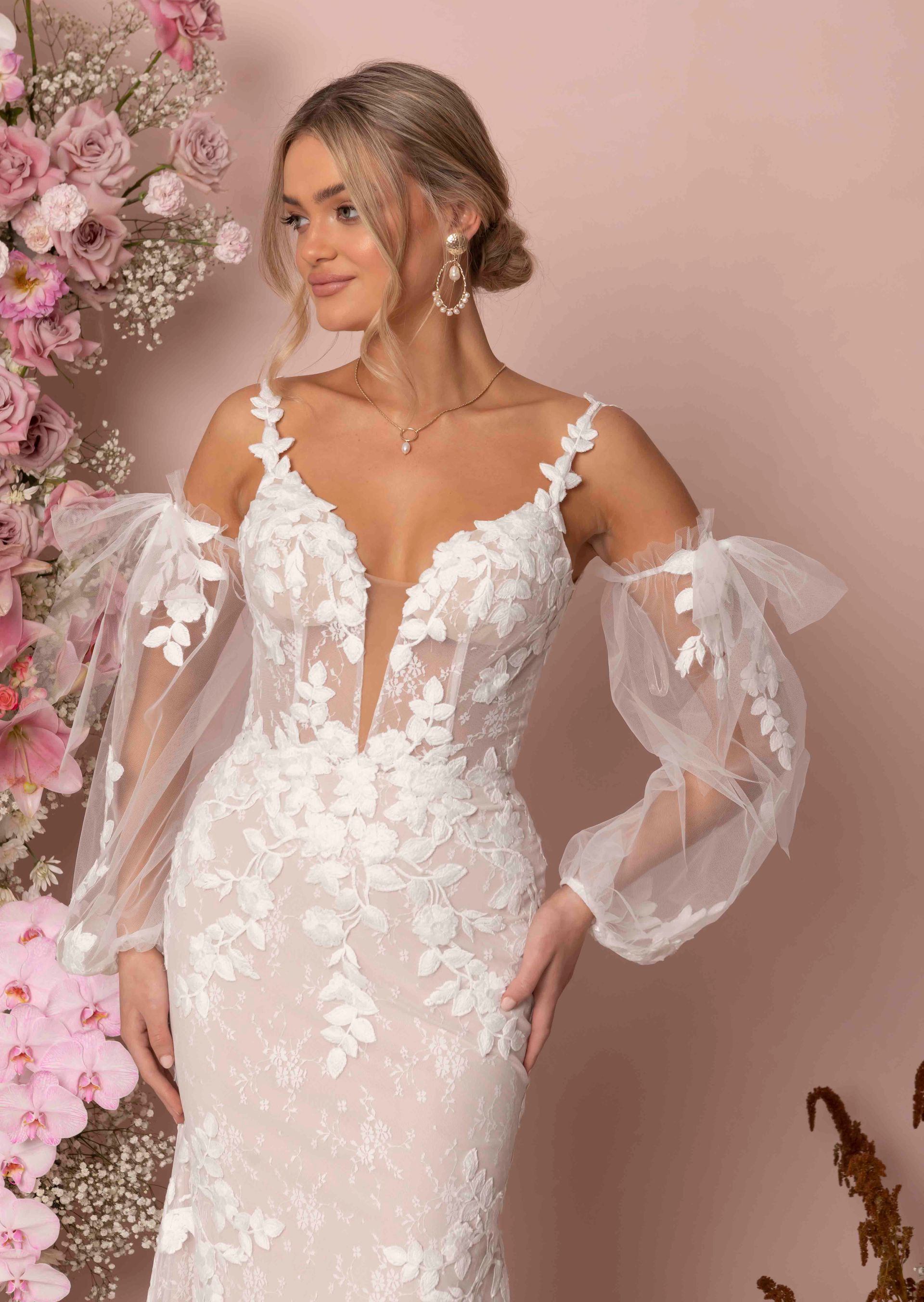 Eine Frau in einem Brautkleid steht vor Blumen.