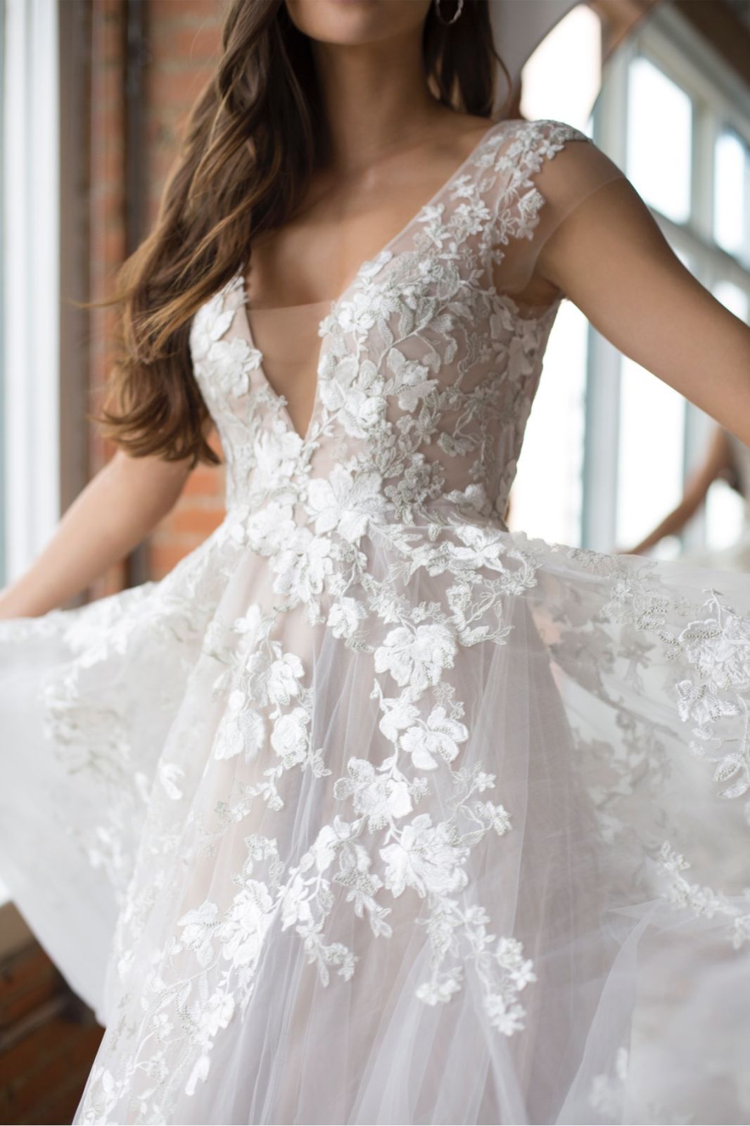 Eine Frau in einem weißen Kleid steht vor Blumen.