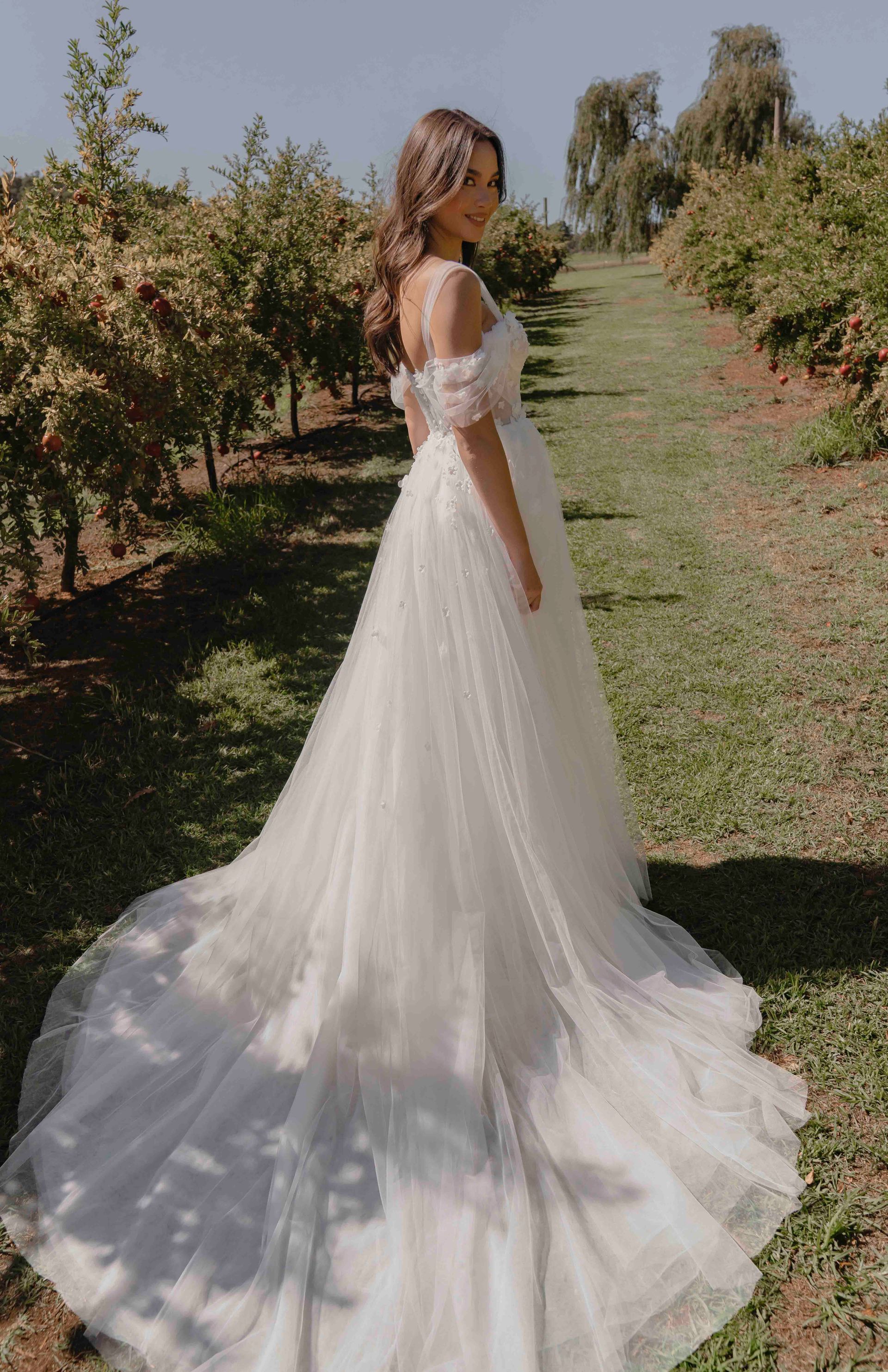 Eine Frau in einem weißen Brautkleid steht auf einem Feld.