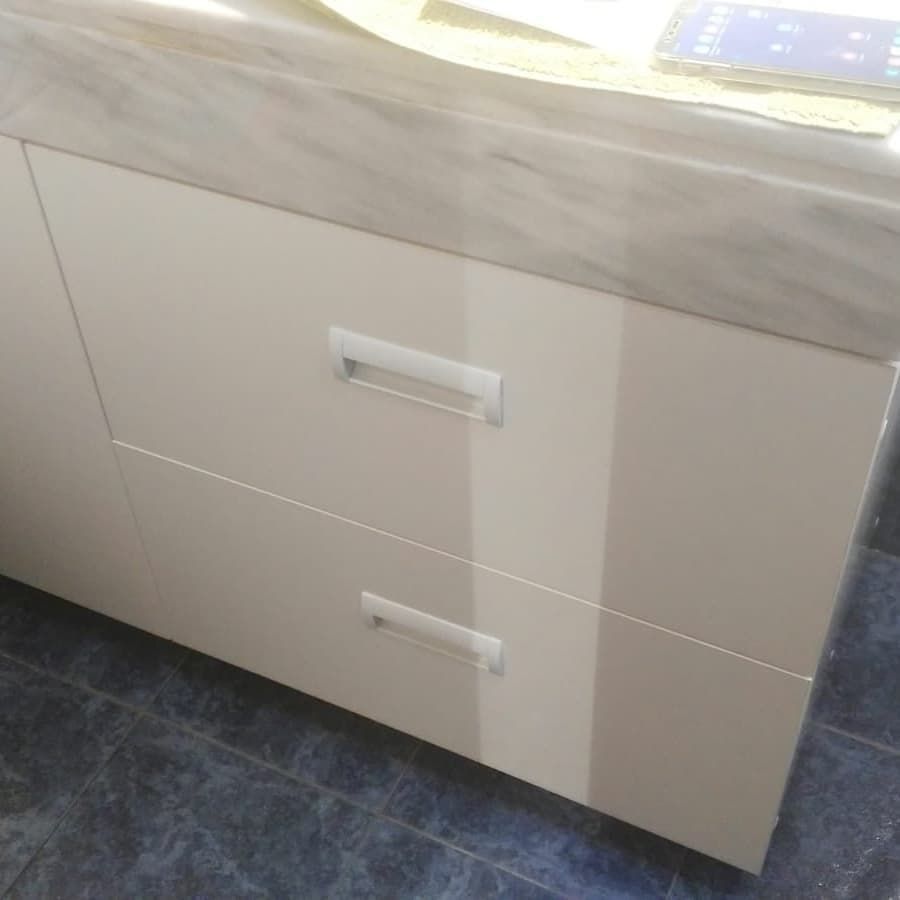 Mueble beige con dos cajones y tiradores plateados bajo encimera de mármol.