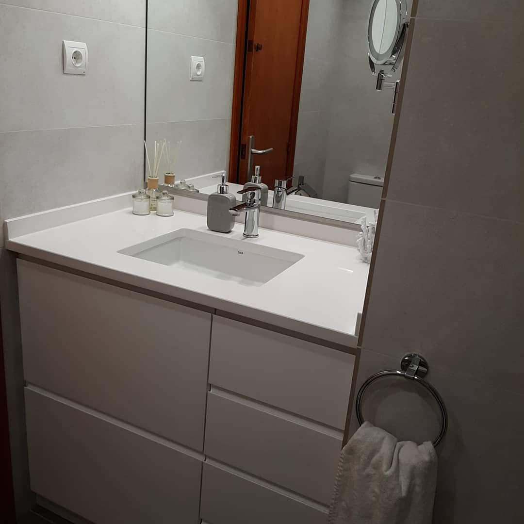 Mueble de baño blanco con lavabo, espejo y toallero.