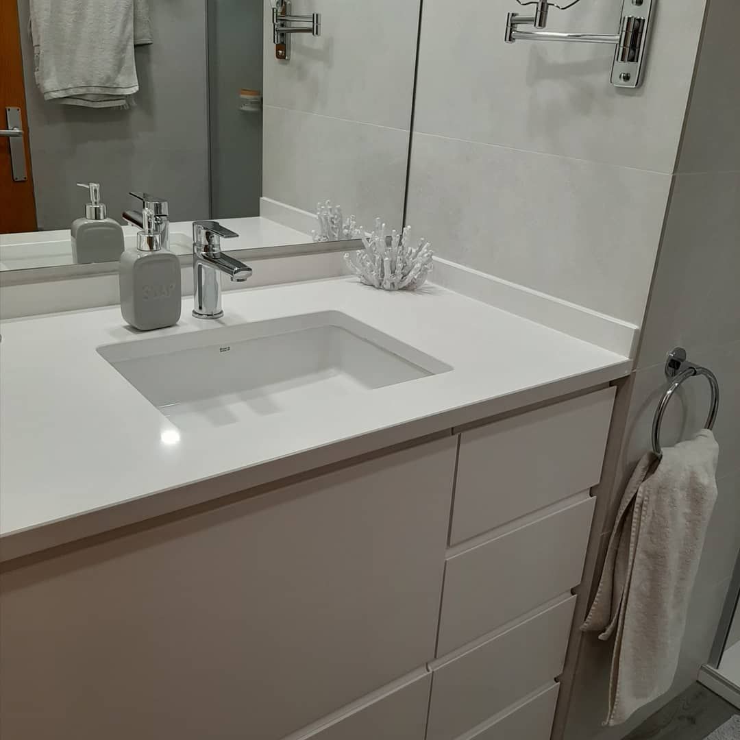 Lavabo y tocador de baño blanco con espejo, dispensador de jabón y toallero.