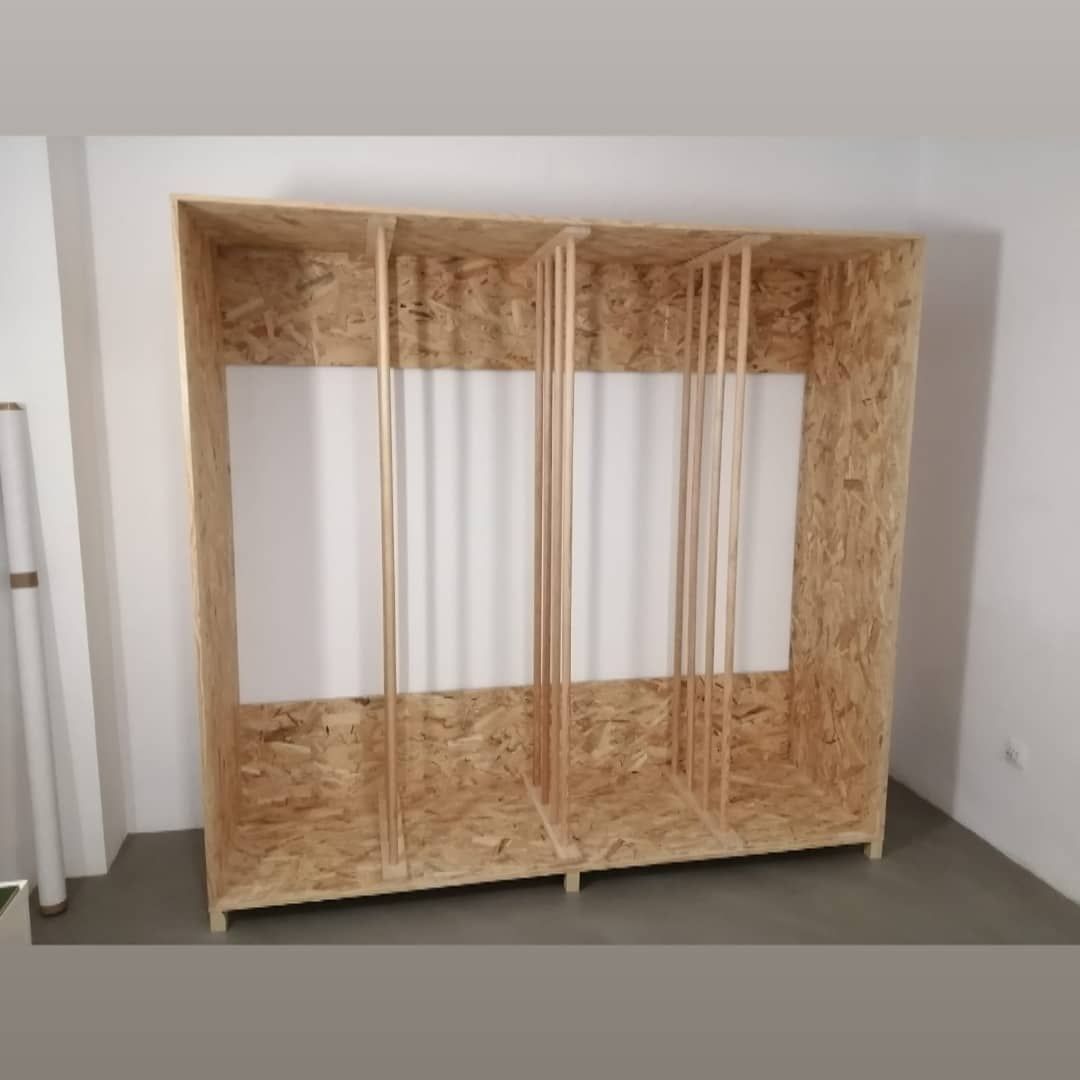 Una estructura de madera con dos compartimentos, soportes de madera y paneles blancos.
