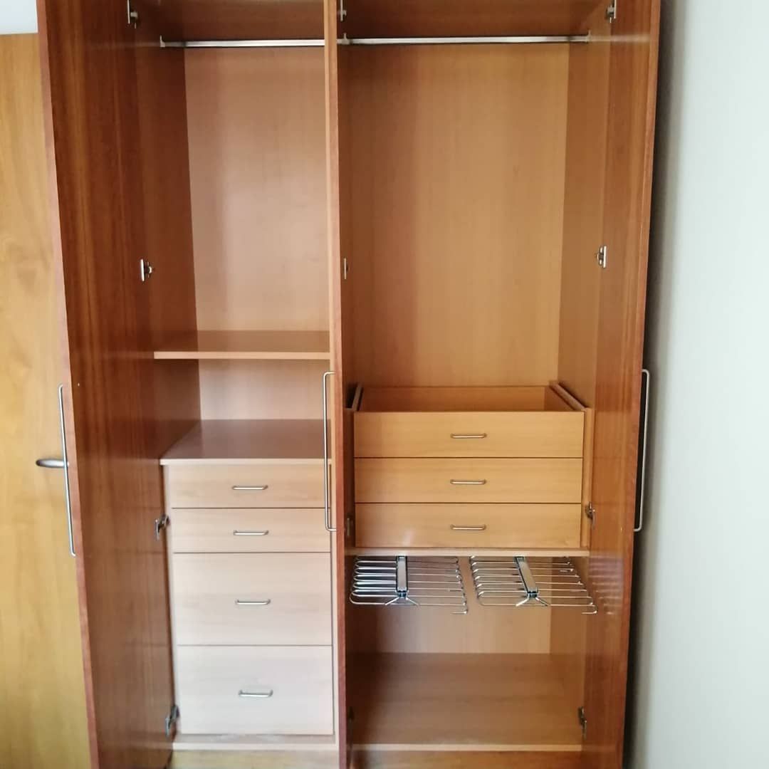 Armario abierto de madera con estantes, cajones y barra para colgar.