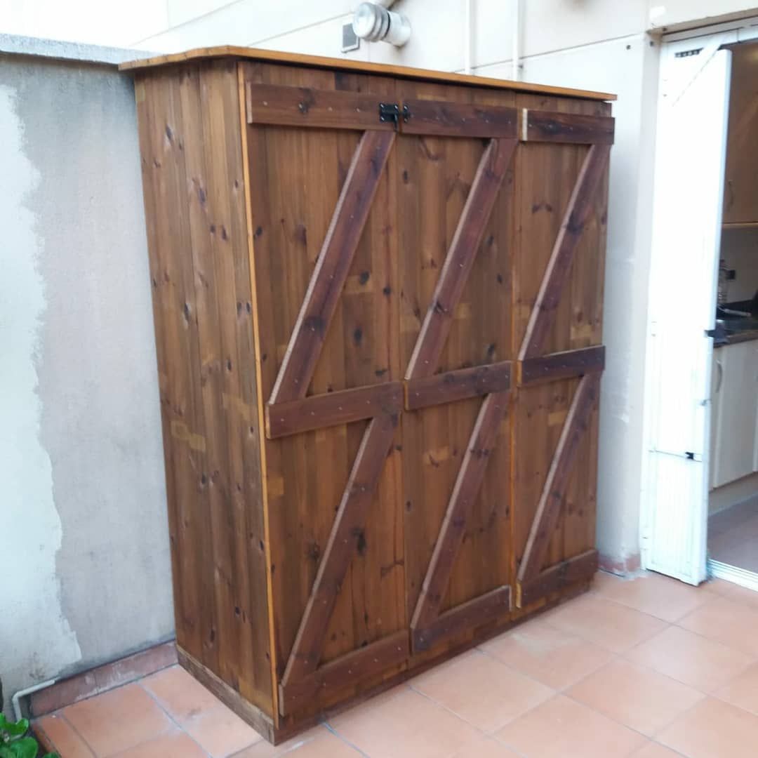 Armario de almacenamiento de madera con puertas teñidas de color oscuro, sobre un patio de baldosas.
