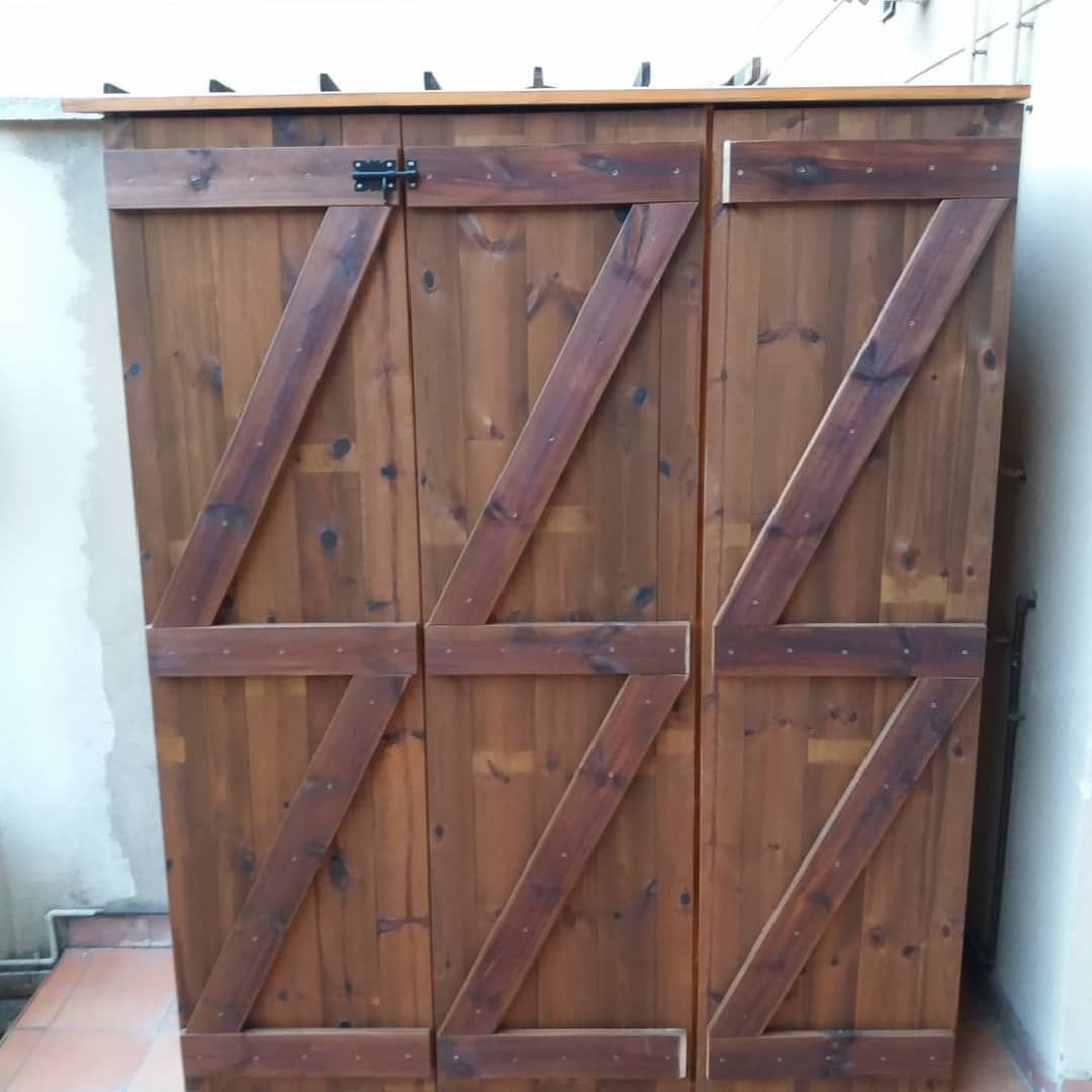 Mueble de almacenaje exterior de madera con tres puertas, teñido en marrón con soportes en forma de Z.