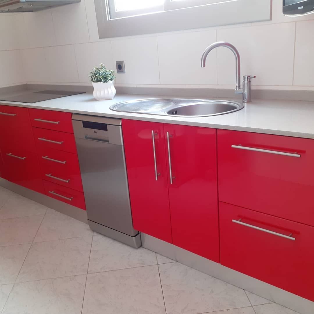 Gabinetes de cocina rojos con electrodomésticos de acero inoxidable, fregadero y encimera.