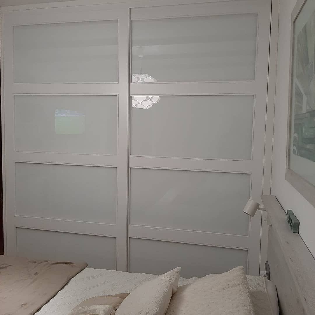 Puertas de armario corredizas blancas con paneles de vidrio esmerilado, en un entorno de dormitorio.
