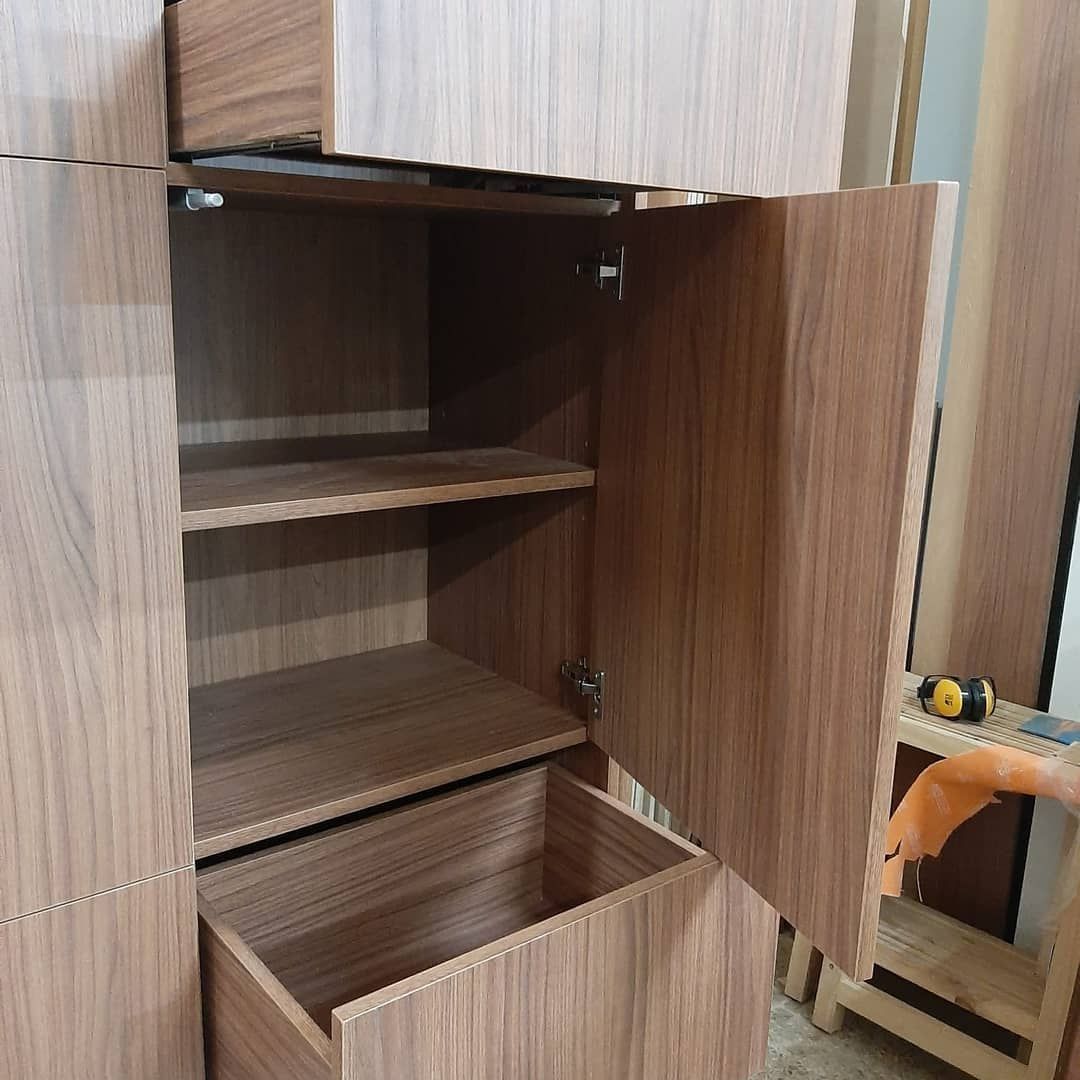 Armario de madera con puerta abierta que revela estantes y un cajón.