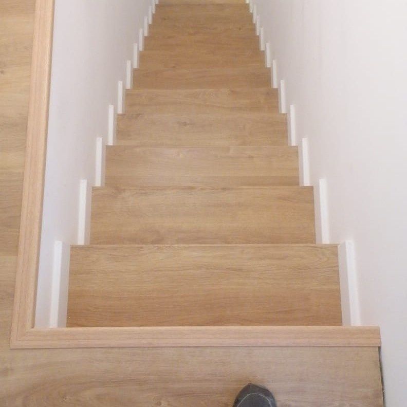 Escalera de madera con paredes laterales blancas.