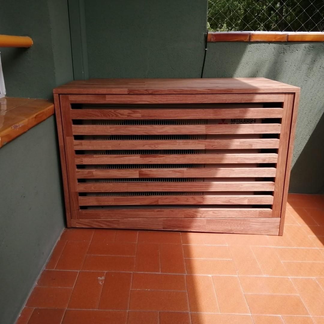 Cubierta de madera para aire acondicionado sobre un patio con baldosas de terracota. La cubierta tiene lamas horizontales.