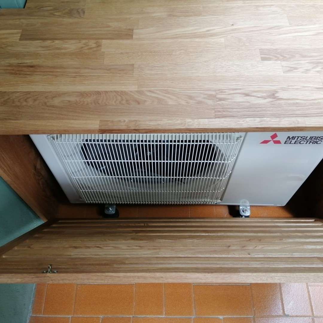 Unidad de aire acondicionado Mitsubishi instalada debajo de un gabinete de madera.