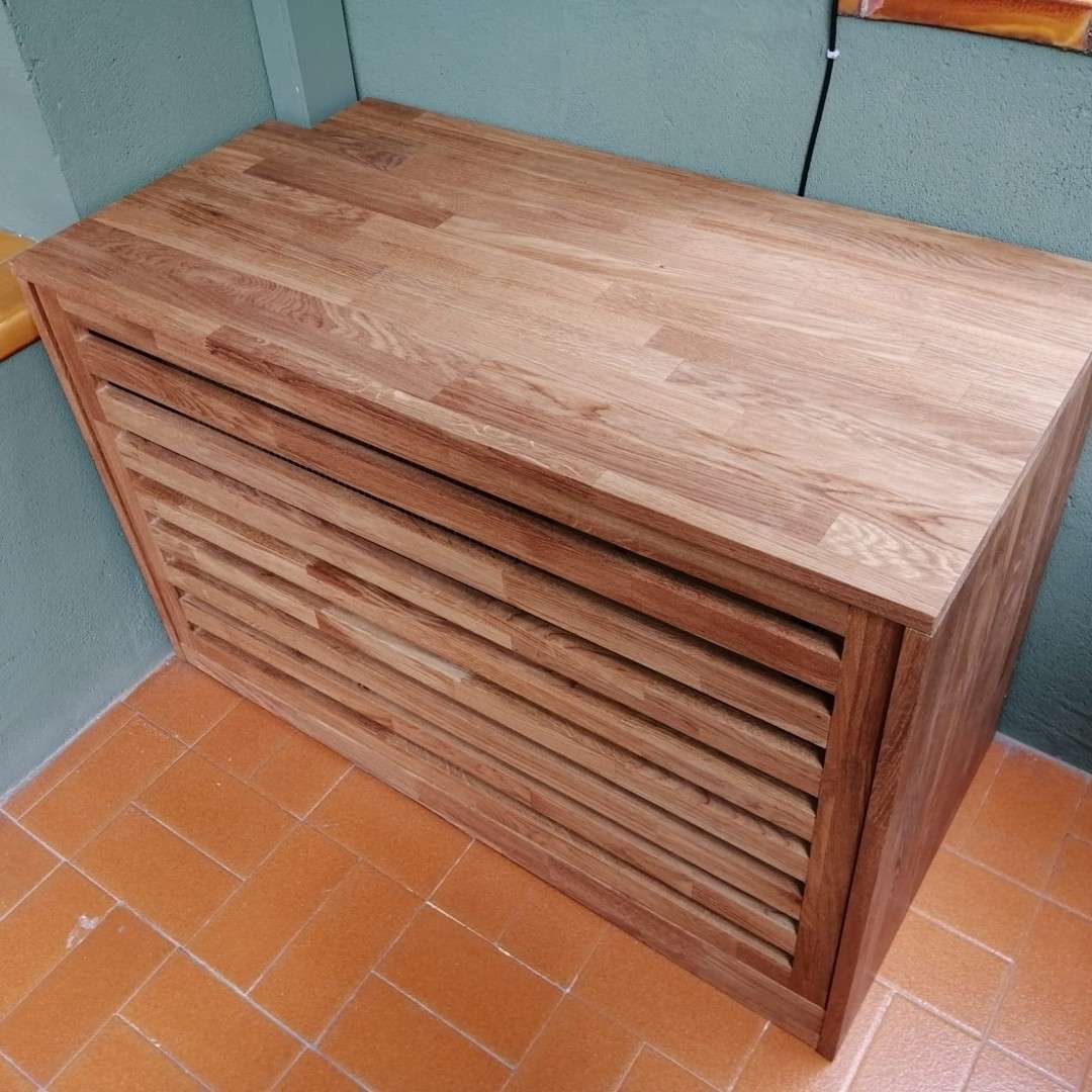 Mueble de madera con frente de lamas, sobre suelo de baldosas.
