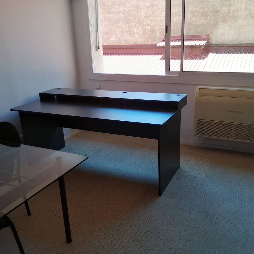 Escritorio de color marrón oscuro con estante elevado en una habitación con ventana y aire acondicionado.