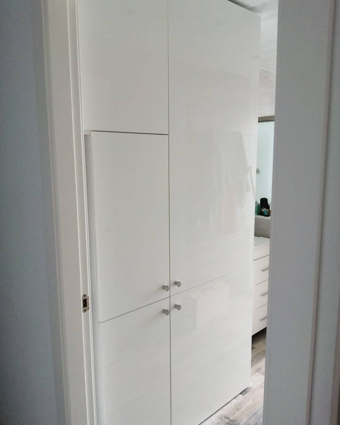 Gabinetes de almacenamiento blancos dentro de una puerta que conduce a un baño.
