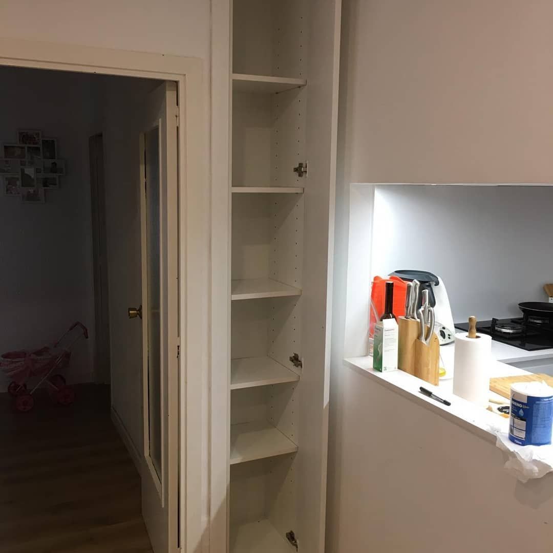 Armario alto blanco con estantes junto a la puerta de la cocina.