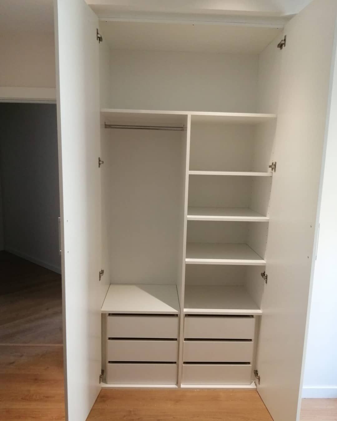 Interior de armario blanco con barra para colgar, estantes y cajones.