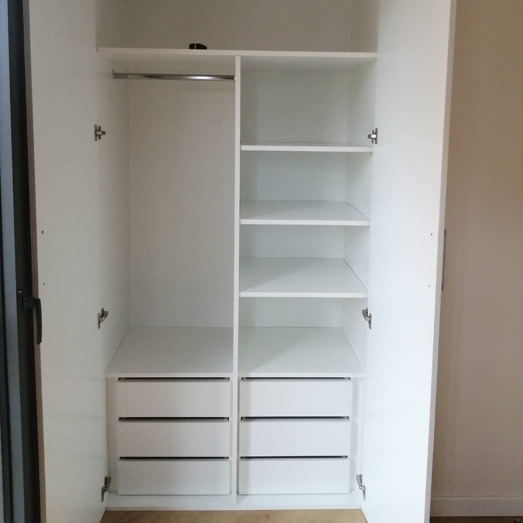 Armario abierto blanco con barra para colgar, estantes y cajones.