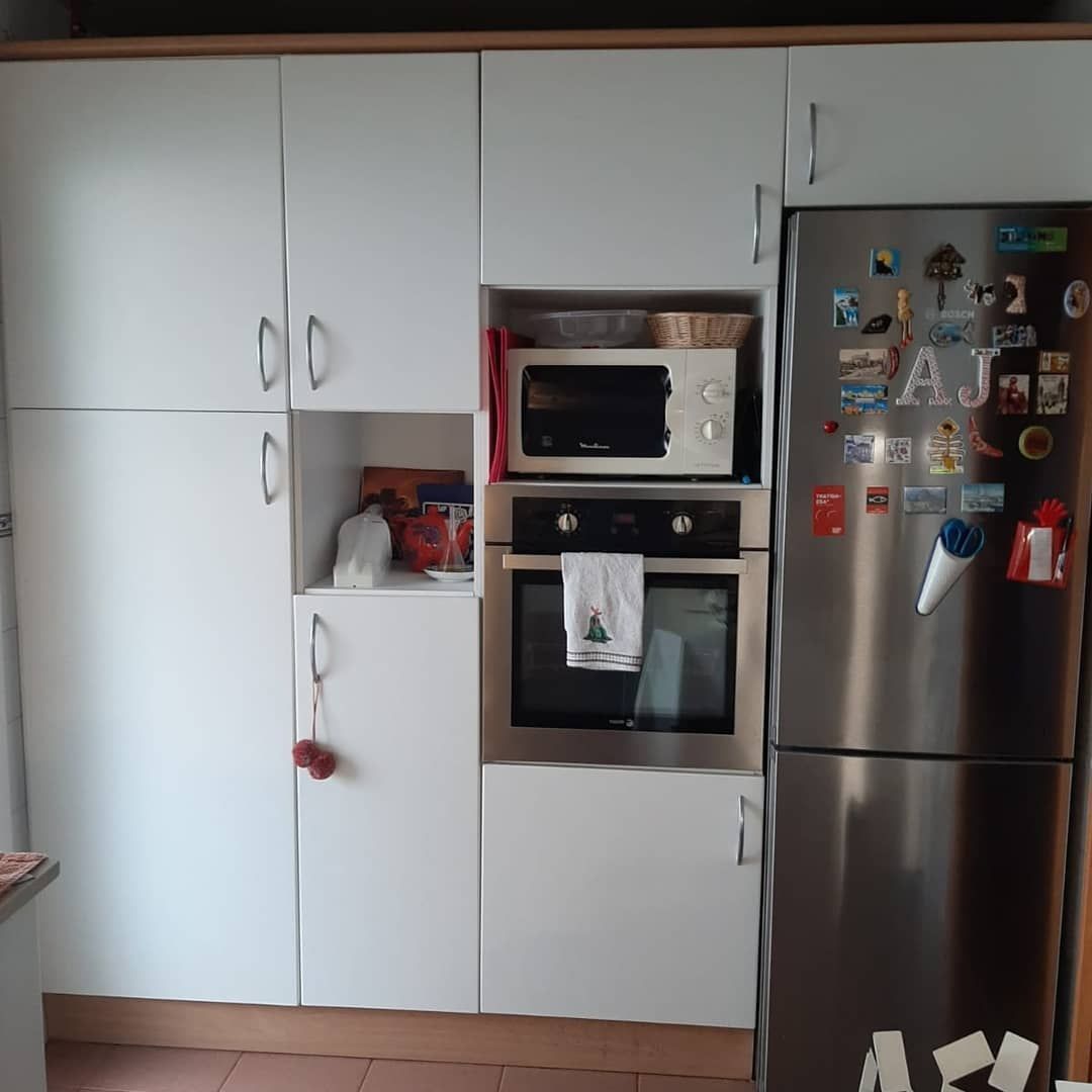 Gabinetes y electrodomésticos de cocina blancos; incluye horno, microondas y refrigerador.